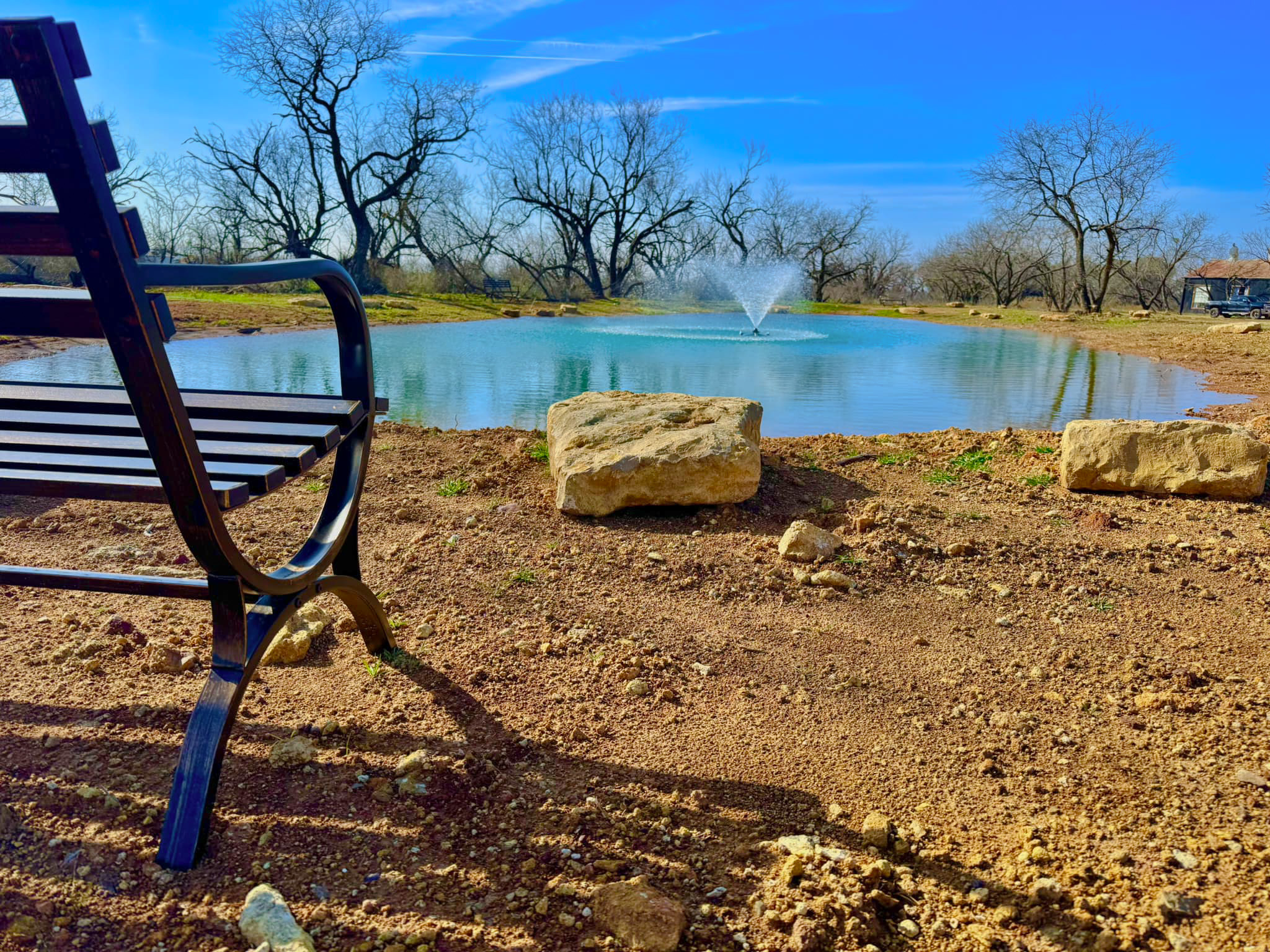 Newly constructed pond with clear blue water on rural property surrounded by open land.
