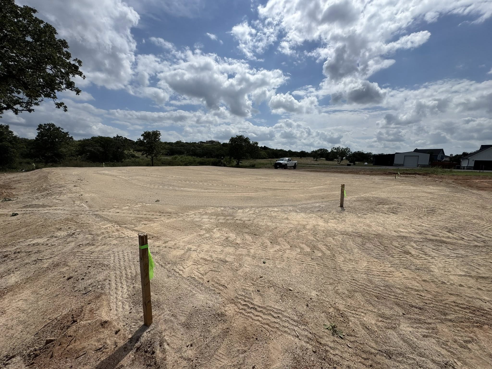 Freshly graded building pad on open property with visible leveling and compaction marks.