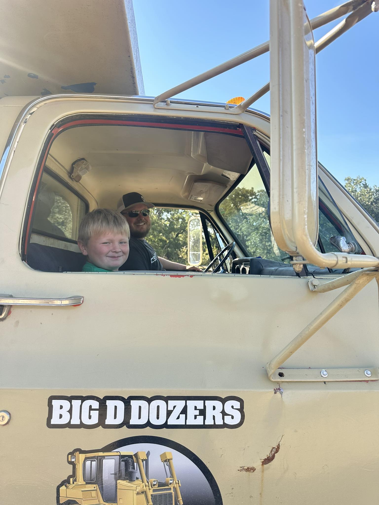 Owner and son sitting inside bulldozer cab